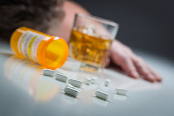 Passed Out Man Behind Scattered Drugs and Glass of Alcohol